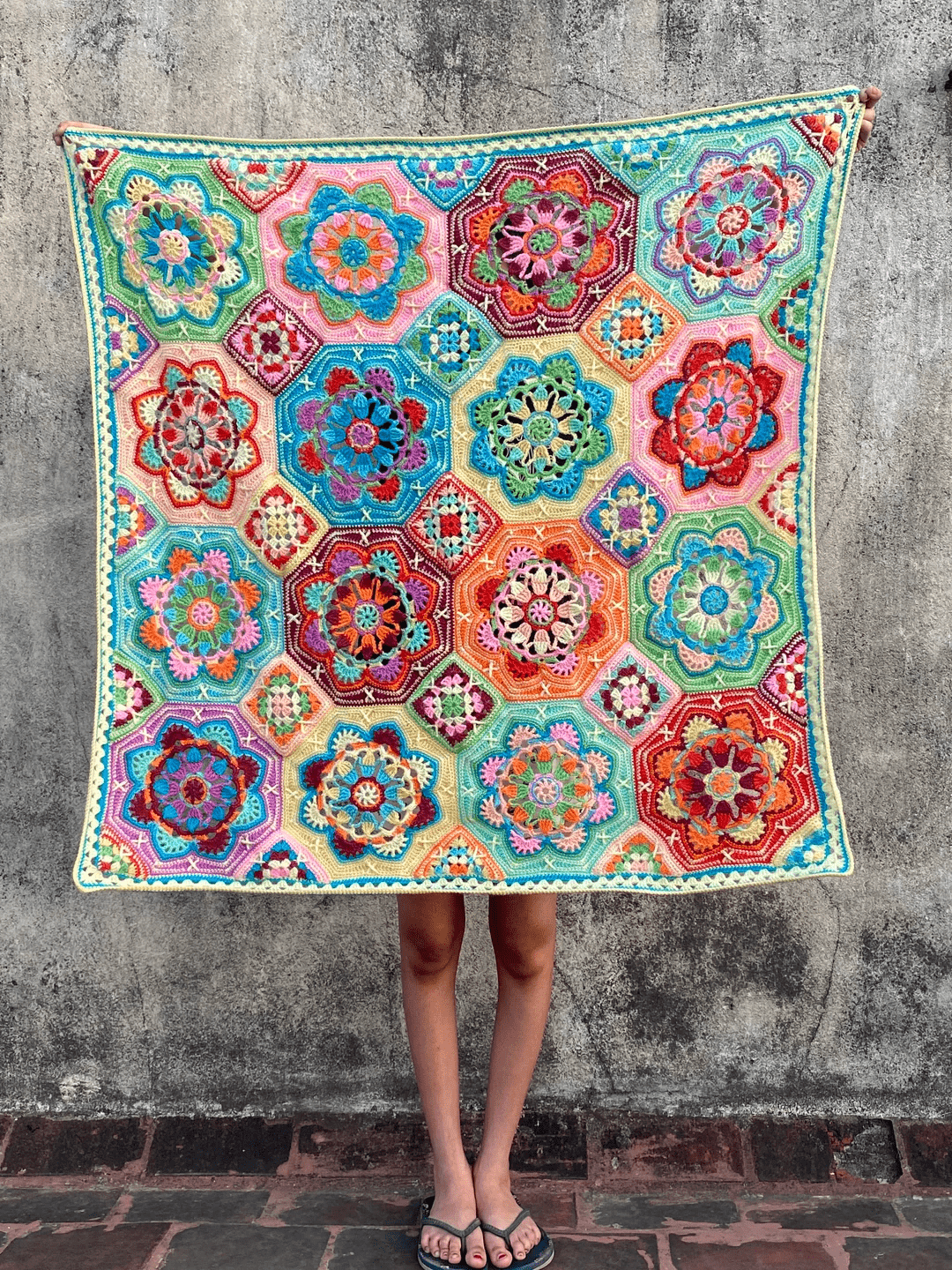 Crochet Persian Tiles blanket held by a person against a concrete wall.