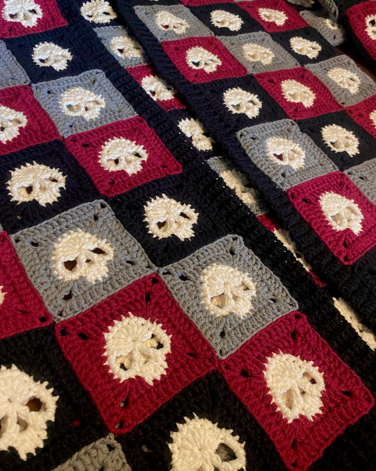 Close-up of a crocheted skull granny squares with square patterns in red, blue, and gray.