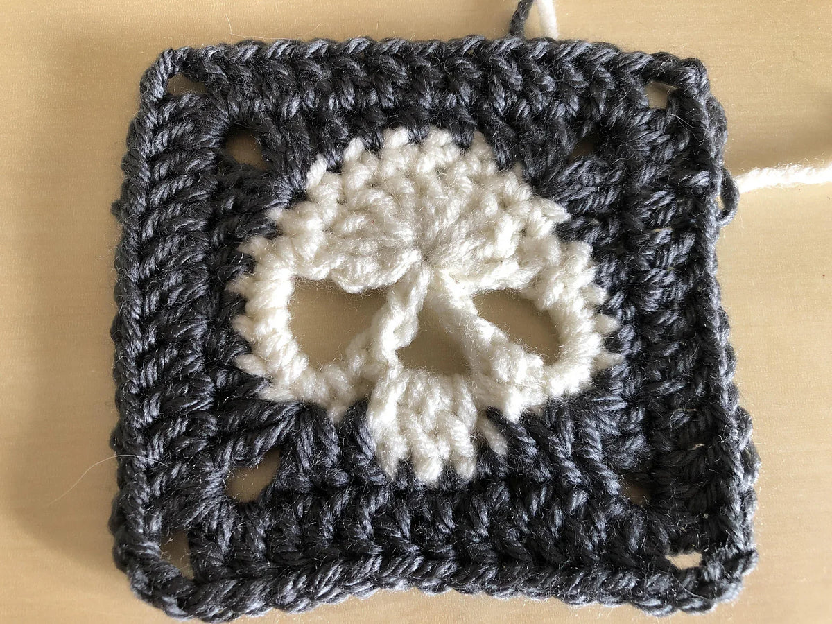 Crocheted skull qranny square with a white center on a beige background
