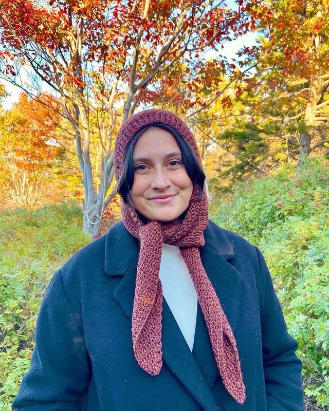Woman wearing crochet hooded scarf – stylish and warm handmade winter accessory.