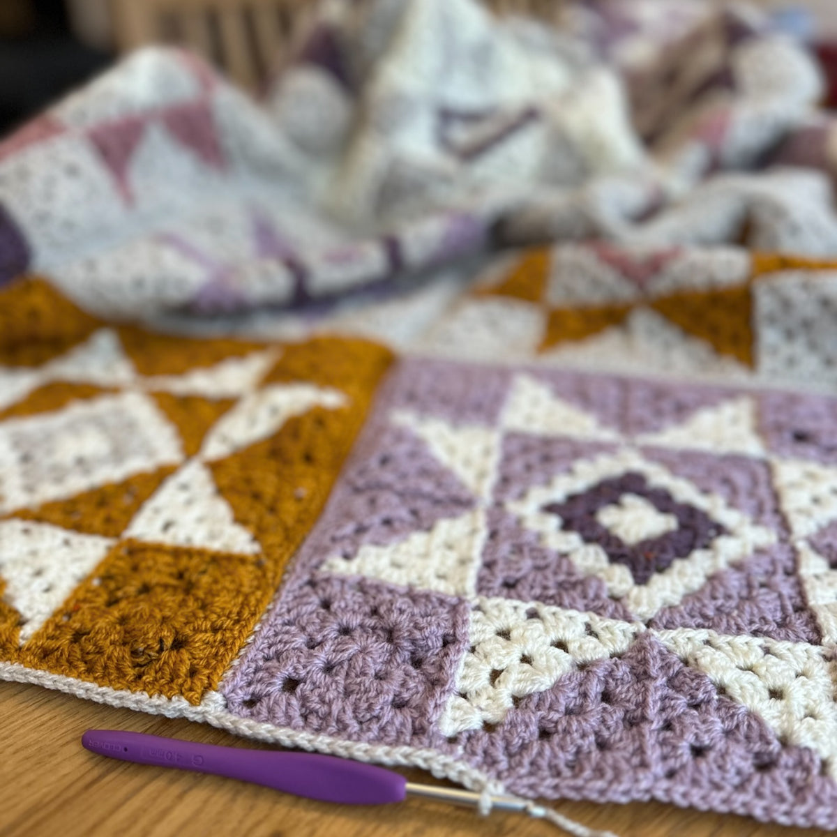 Crocheted quiet sky blanket with geometric pattern on a wooden surface