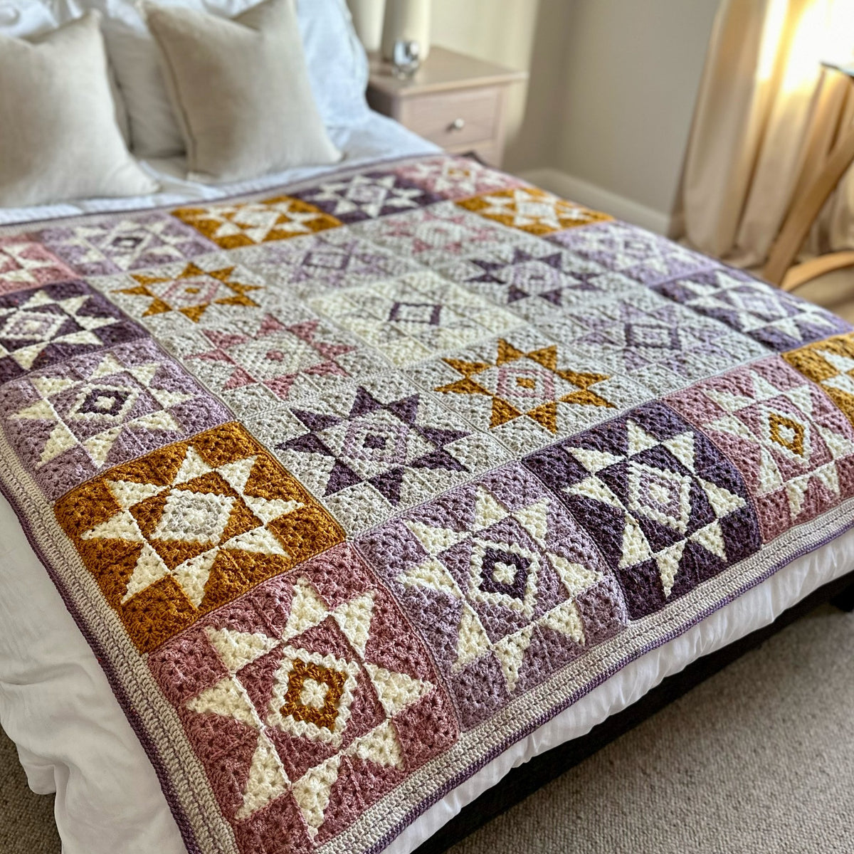 Star crochet squares used in a quiet sky crochet blanket design on a bed in a bedroom setting