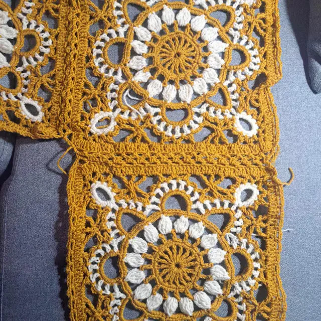 Close-up of a crocheted Turkish granny square with yellow and white colors on a blue background